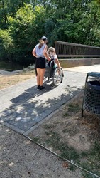 Kind mit Rollstuhl, das von einem anderen Kind geschoben wird