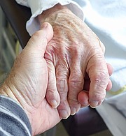 Foto: Zu sehen sind die Hände zweier Personen: die Hand einer jüngeren Person hält die Hand einer älteren Person.