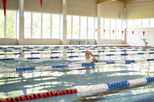 Ein Schwimmer im Hallenbad-Wasser zieht seine Bahnen