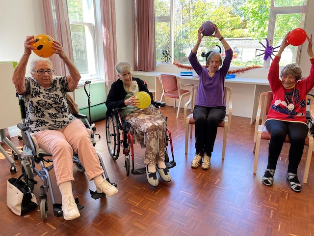 Foto: Eine Gruppe älterer Frauen macht im Sitzen Gymnastikübungen.