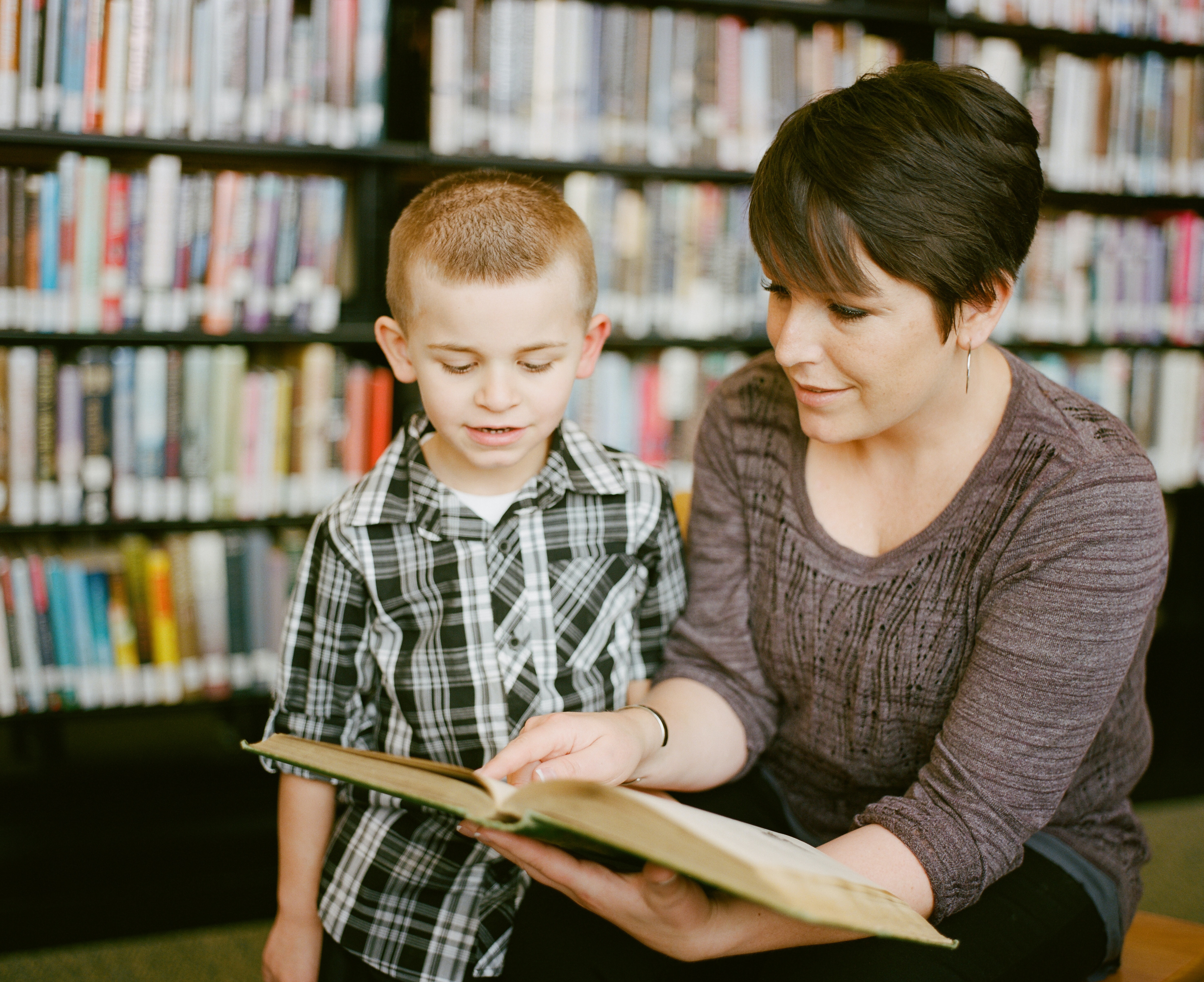 Foto: Ein Kind und eine Frau schauen gemeinsam in ein Buch.