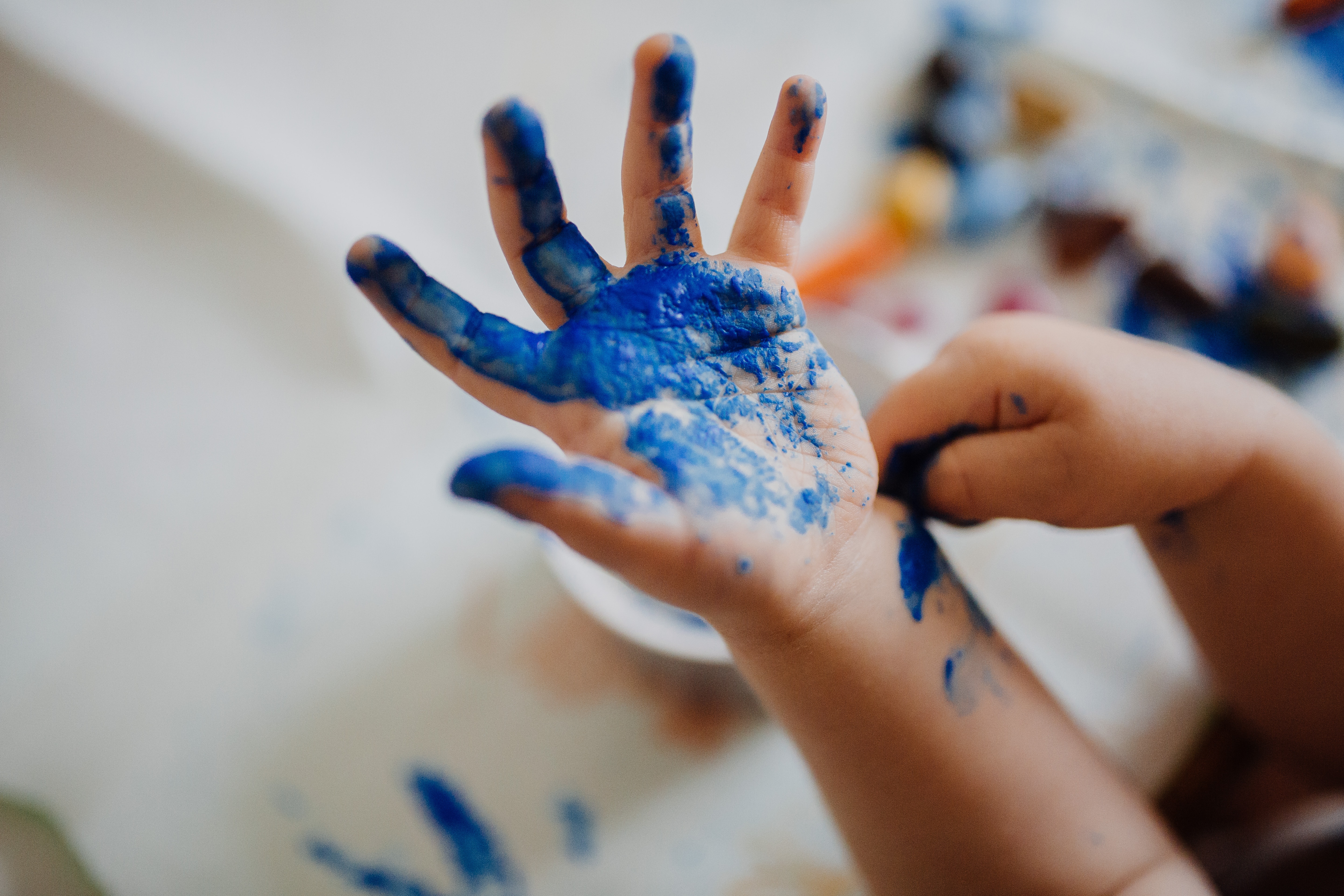 Foto: mit blauer Farbe bemalte Kinderhand.